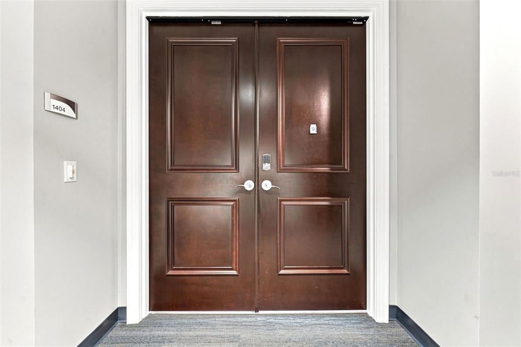 A pair of dark wood double doors with silver hardware and a unit number sign — 1209 E CUMBERLAND AVENUE UNIT 1404, TAMPA, FL