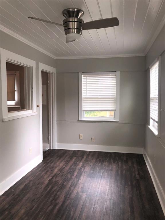 A room with dark wood-look flooring, light gray walls, a ceiling fan, and two windows — 309 S PARK AVENUE UNIT U, SANFORD, FL