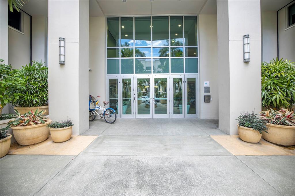 The exterior entrance of a building features glass doors, large planters, and a bicycle — 400 4TH AVENUE S UNIT 701, ST PETERSBURG, FL