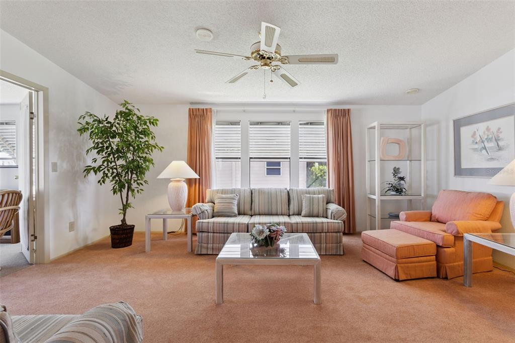 A living room features a striped sofa, a peach armchair with ottoman, and a ceiling fan — 1615 PINEHURST DRIVE, LADY LAKE, FL