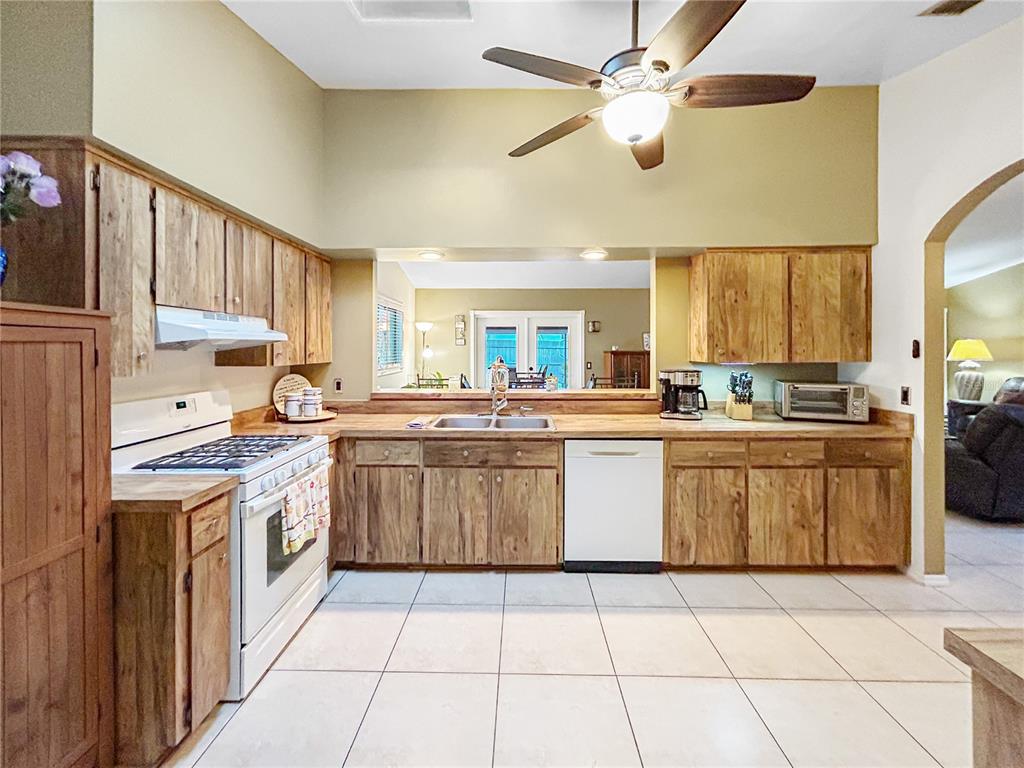 A kitchen features light wood cabinets, white appliances, a ceiling fan, and tiled flooring — 1616 E SANDPIPER TRAIL, CASSELBERRY, FL