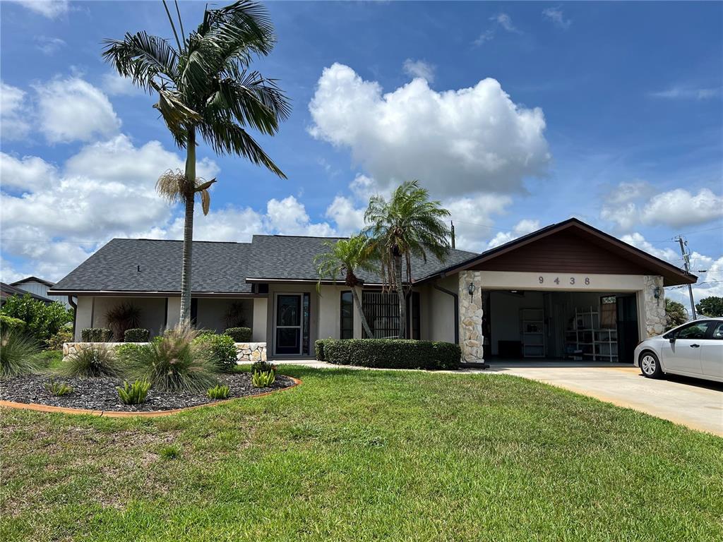 A single-story house with a stone-accented garage, palm trees, and a landscaped front yard — 9438 CRUGAR, ENGLEWOOD, FL