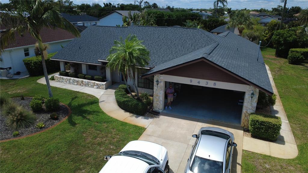 An aerial view shows a single-story house with a dark shingled roof and stone accents — 9438 CRUGAR, ENGLEWOOD, FL