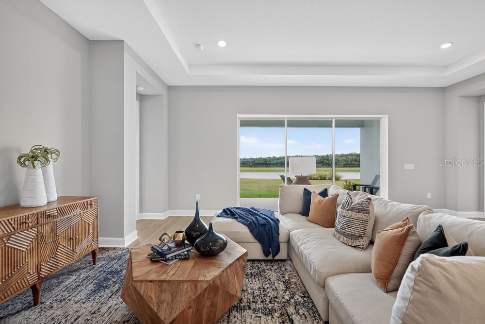 A kitchen features white cabinetry, stainless steel appliances, a large island, and three pendant lights — 5676 NEVIS TERRACE, KISSIMMEE, FL