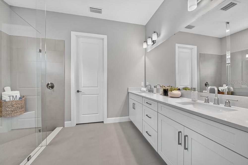 An open-concept living room and kitchen featuring a large island, chandeliers, and arched wall mirrors — 5676 NEVIS TERRACE, KISSIMMEE, FL