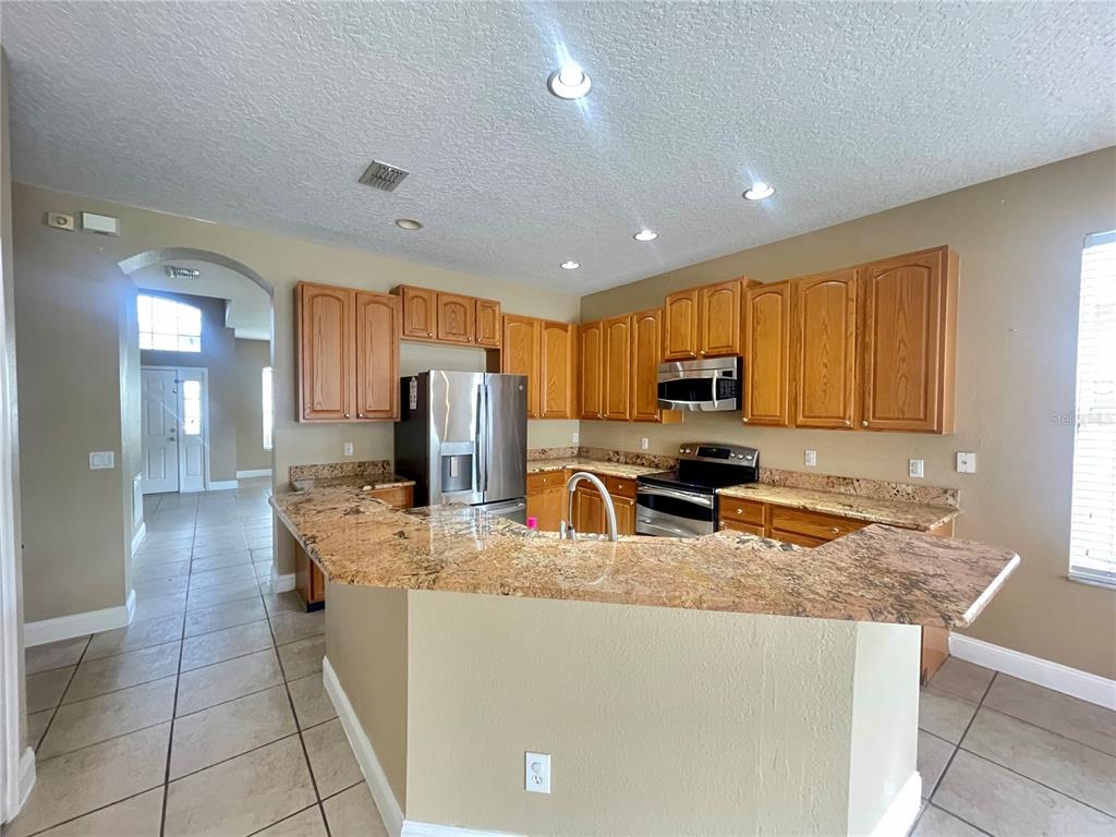 A kitchen features light wood cabinets, granite countertops, and tile flooring — 10366 CYPRESS KNEE CIRCLE, ORLANDO, FL