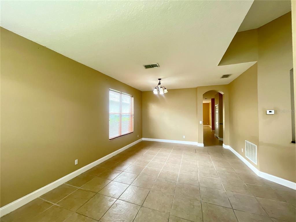 An empty dining room features tan walls, tile flooring, a window with blinds, and a chandelier — 10366 CYPRESS KNEE CIRCLE, ORLANDO, FL