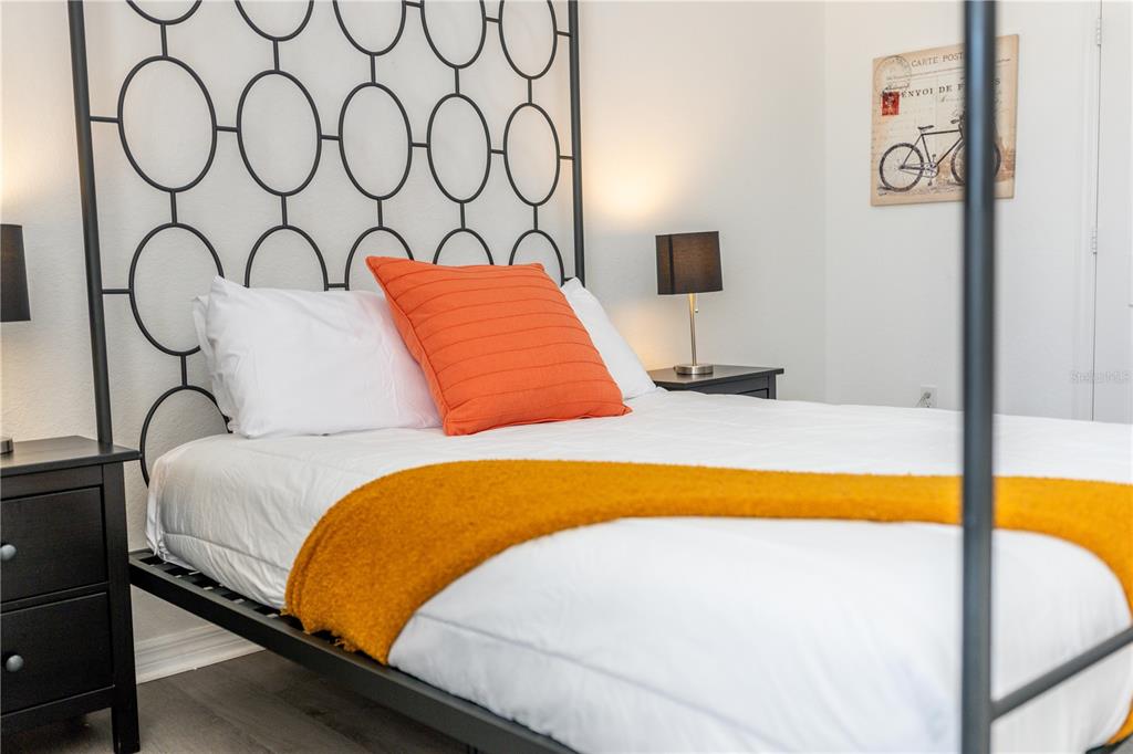A bedroom features a metal bed frame with a circular pattern headboard and orange accents — 437 CADIZ LOOP, DAVENPORT, FL