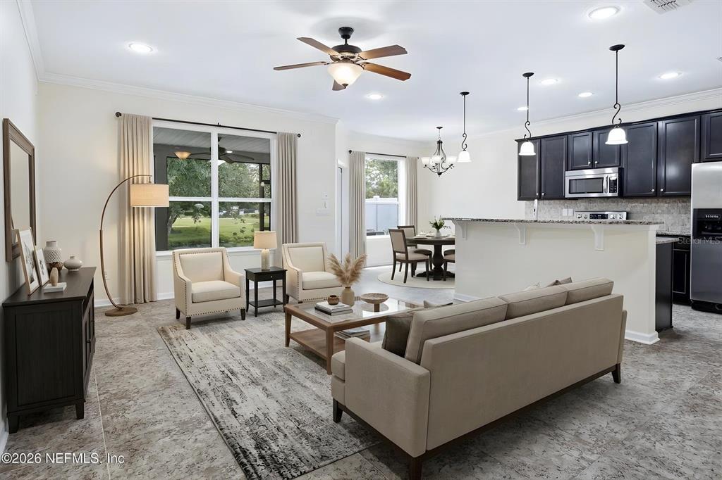 An open-concept living room and kitchen feature tile flooring, neutral furniture, and dark cabinetry — 435 WALNUT DRIVE, ST JOHNS, FL