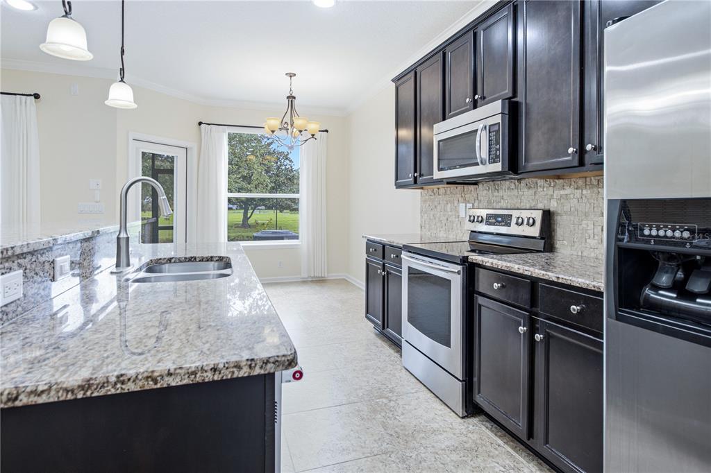 A kitchen features dark wood cabinets, granite countertops, stainless steel appliances, and a breakfast nook — 435 WALNUT DRIVE, ST JOHNS, FL