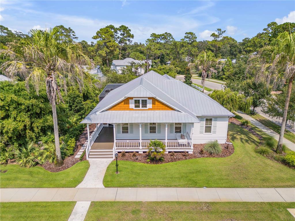 An elevated single-story house with a metal roof, front porch, and palm trees in front — 1902 KINGS END, NEW SMYRNA BEACH, FL
