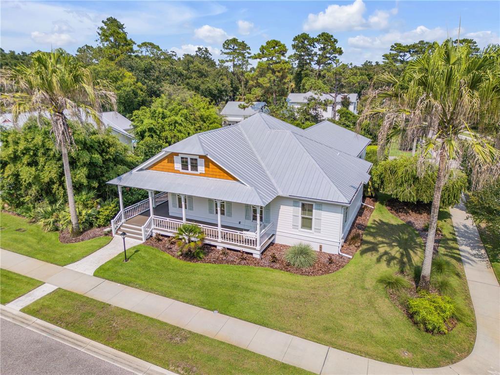 An aerial view shows a white house with a metal roof and a wrap-around porch — 1902 KINGS END, NEW SMYRNA BEACH, FL