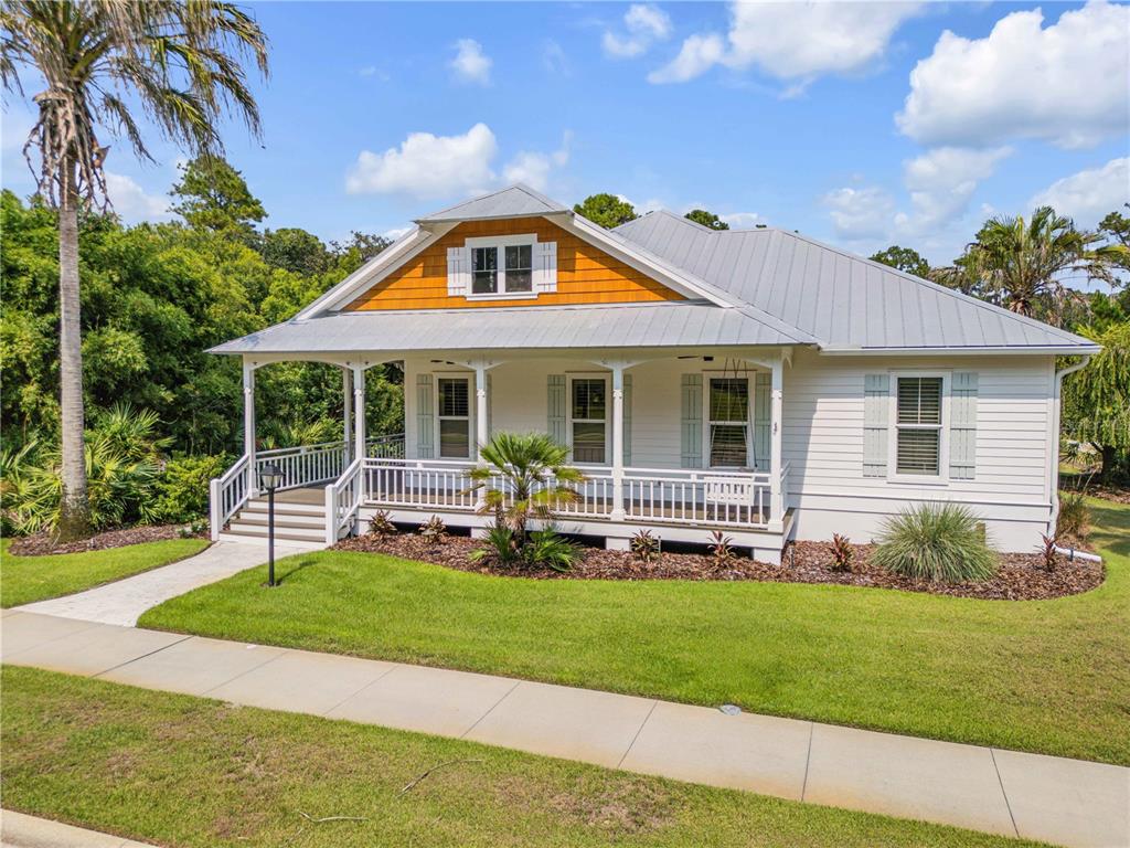 A white house with a metal roof, front porch, and orange gable siding — 1902 KINGS END, NEW SMYRNA BEACH, FL