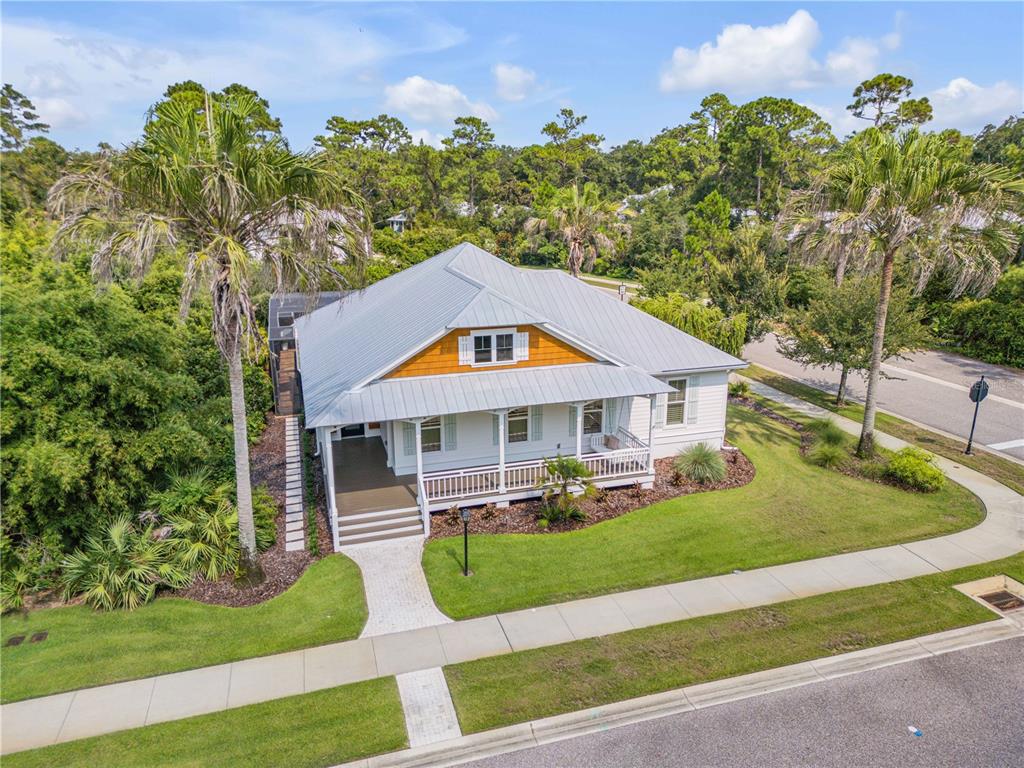 An elevated white house with a metal roof and a front porch sits near a road — 1902 KINGS END, NEW SMYRNA BEACH, FL