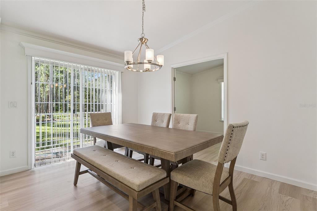 A dining room features a wooden table with a bench and chairs under a chandelier — 1161 LAKE HARNEY WOODS BOULEVARD, MIMS, FL