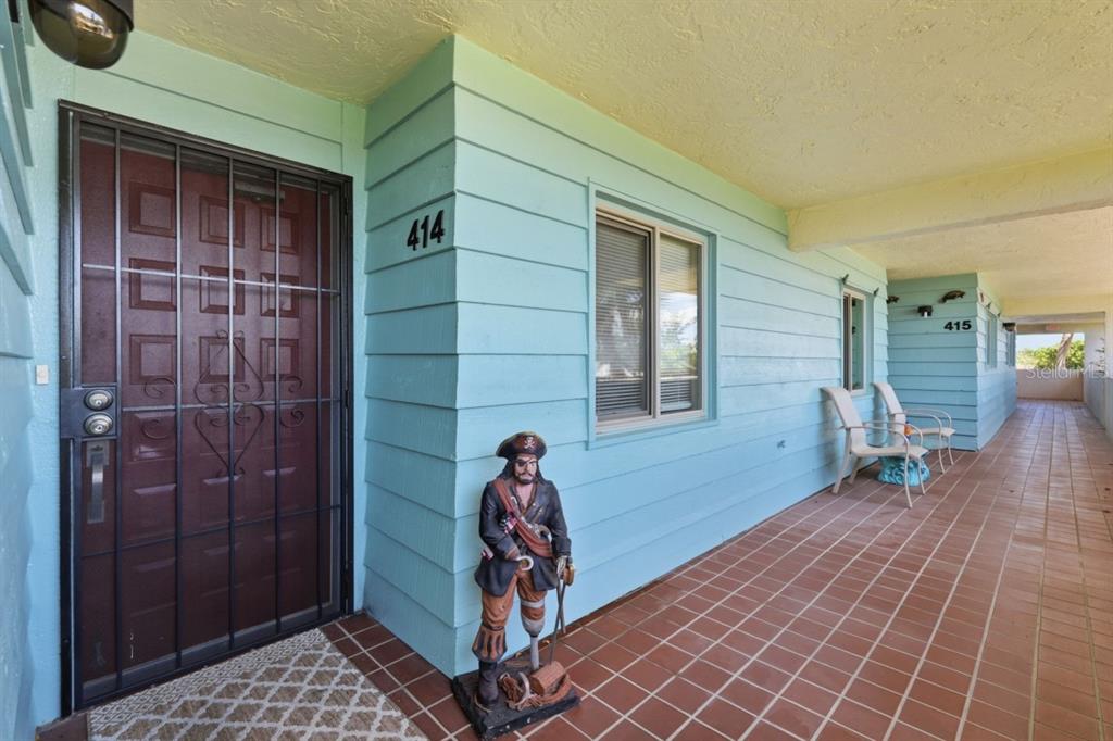 A light blue exterior wall features a pirate statue, a dark door, and tiled flooring — 9604 CORTEZ ROAD W UNIT 414, BRADENTON, FL