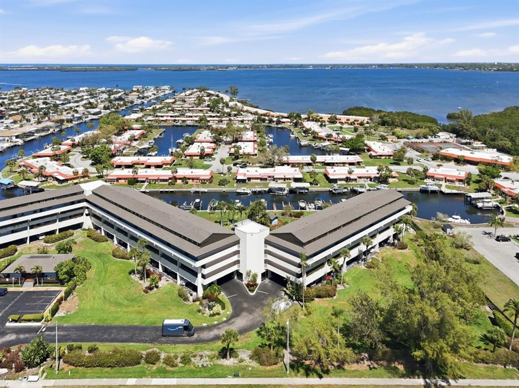 An aerial view shows a multi-story apartment building with a parking lot and boat slips — 9604 CORTEZ ROAD W UNIT 414, BRADENTON, FL