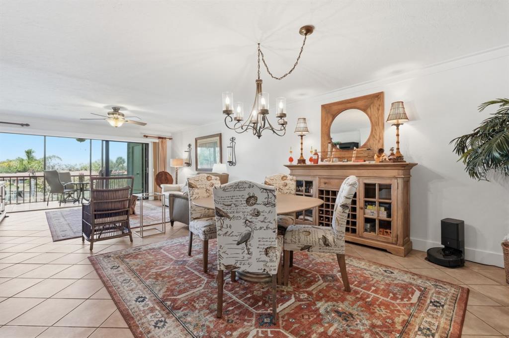 A dining area features a round table, patterned chairs, a wooden sideboard, and tile flooring — 9604 CORTEZ ROAD W UNIT 414, BRADENTON, FL
