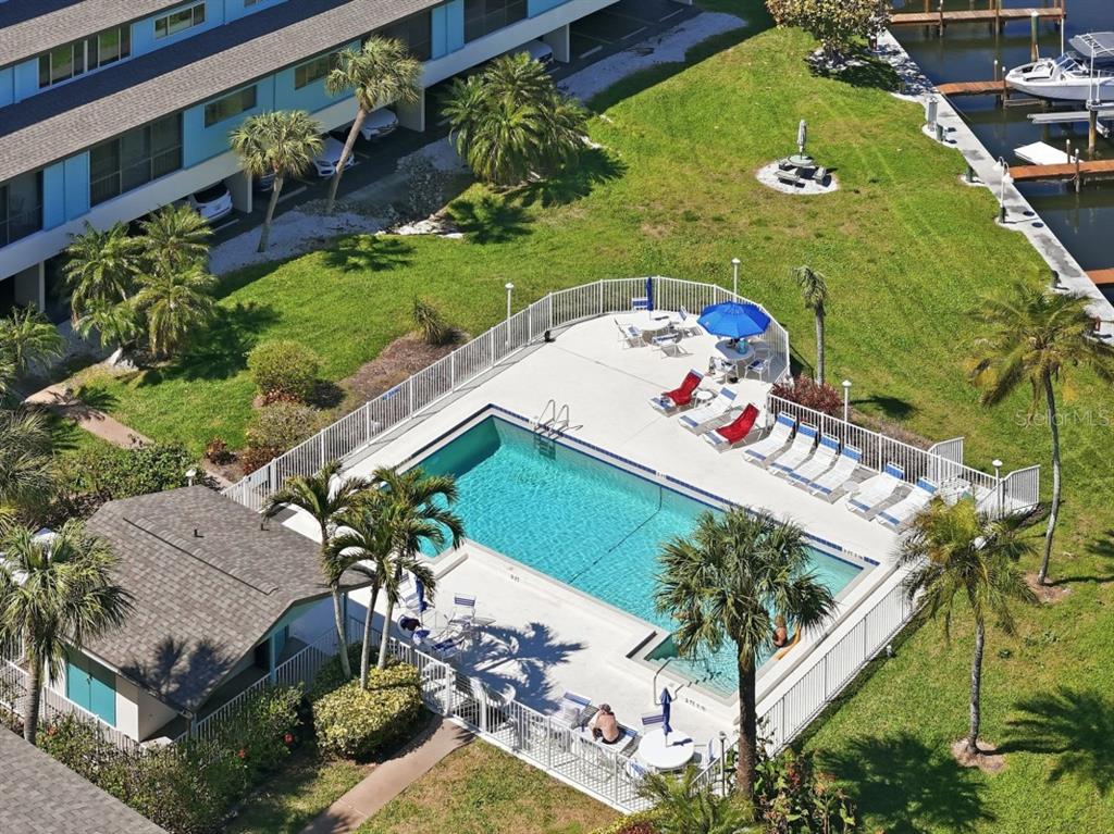 An aerial view shows a rectangular swimming pool with lounge chairs inside a fenced enclosure — 9604 CORTEZ ROAD W UNIT 414, BRADENTON, FL