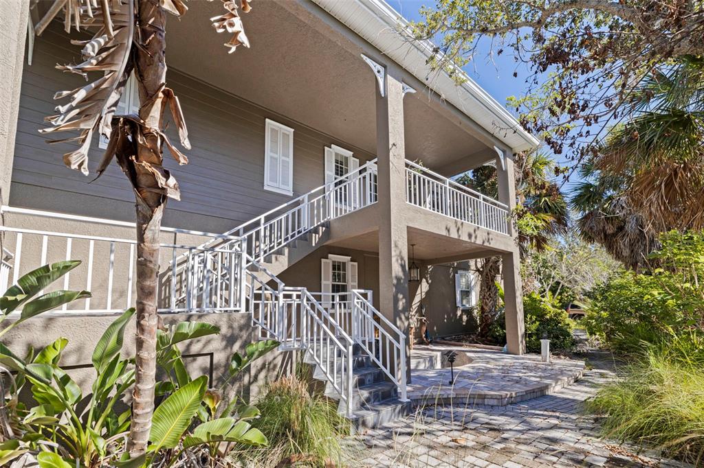 An exterior view of a two-story house with a white staircase leading to a balcony — 2000 BAYVIEW DRIVE, TIERRA VERDE, FL