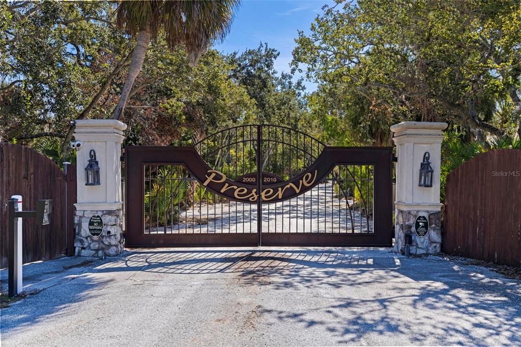 A metal gate with the word Preserve sits between two stone pillars under large trees — 2000 BAYVIEW DRIVE, TIERRA VERDE, FL