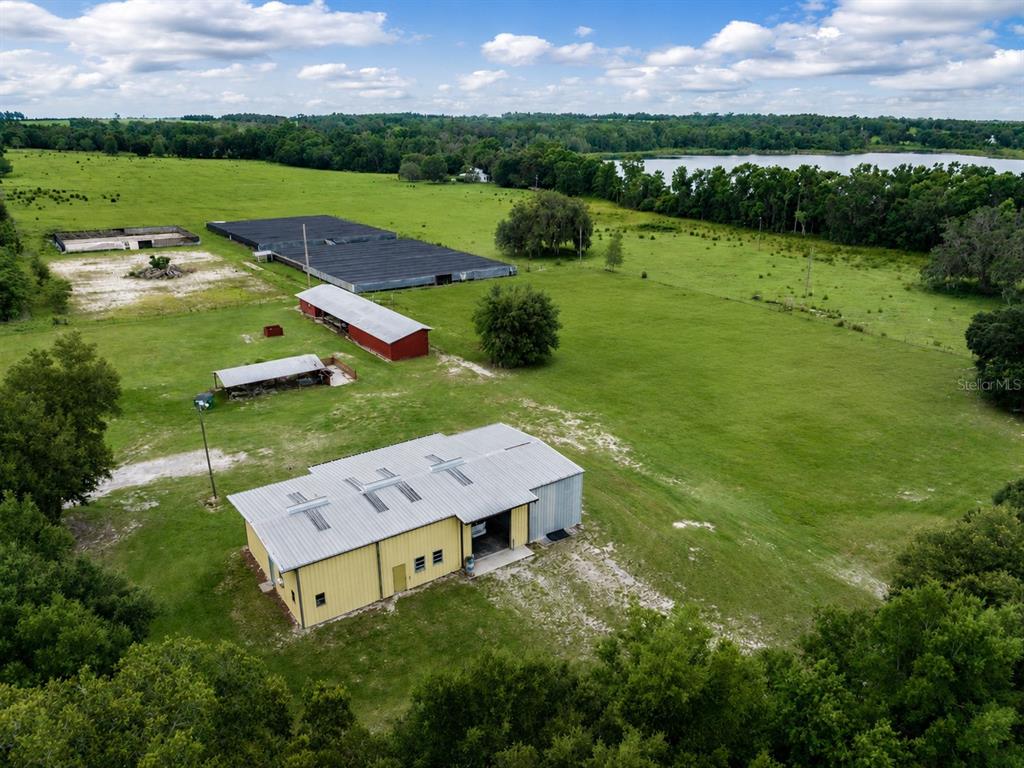 An aerial view shows a rural property with several outbuildings, a large pasture, and a lake — 33144 MCCABE ROAD, SAN ANTONIO, FL