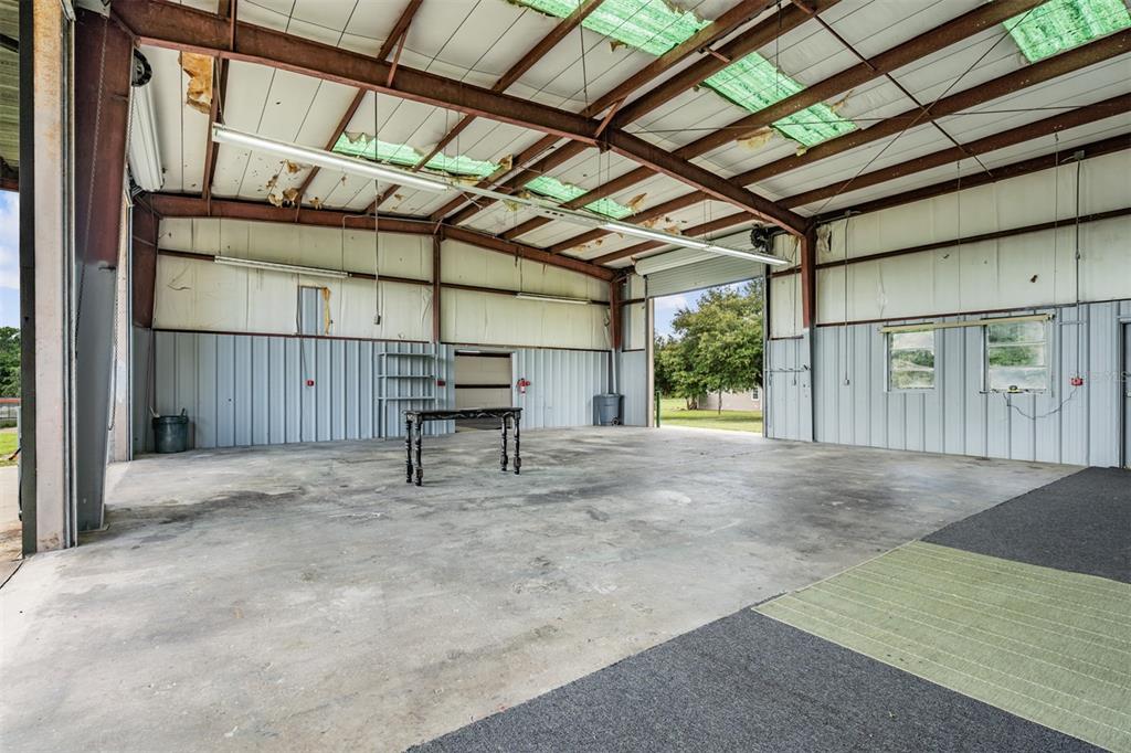 An open-concept metal warehouse features a concrete floor, exposed steel beams, and translucent roof panels — 33144 MCCABE ROAD, SAN ANTONIO, FL