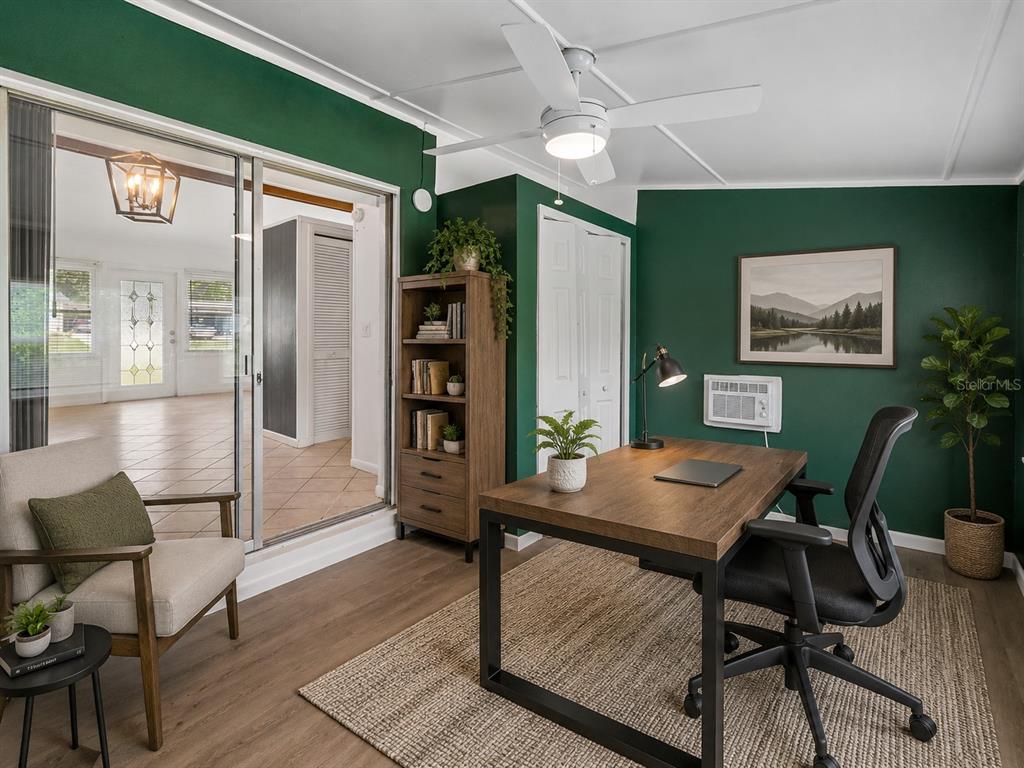 A home office with a dark green accent wall, wood desk, and sliding glass doors — 572 E NORMANDY BOULEVARD, DELTONA, FL