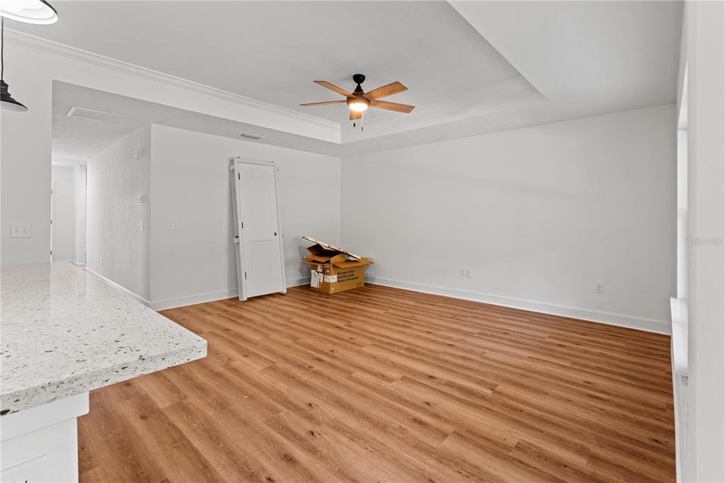 A kitchen features white cabinets, granite countertops, a center island, and wood-look flooring — 10131 NE 80TH STREET, BRONSON, FL