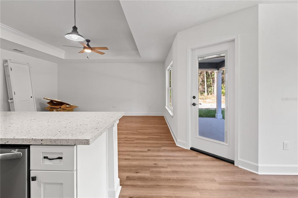 A kitchen with white cabinets, granite countertops, and an island opens to a dining area — 10131 NE 80TH STREET, BRONSON, FL