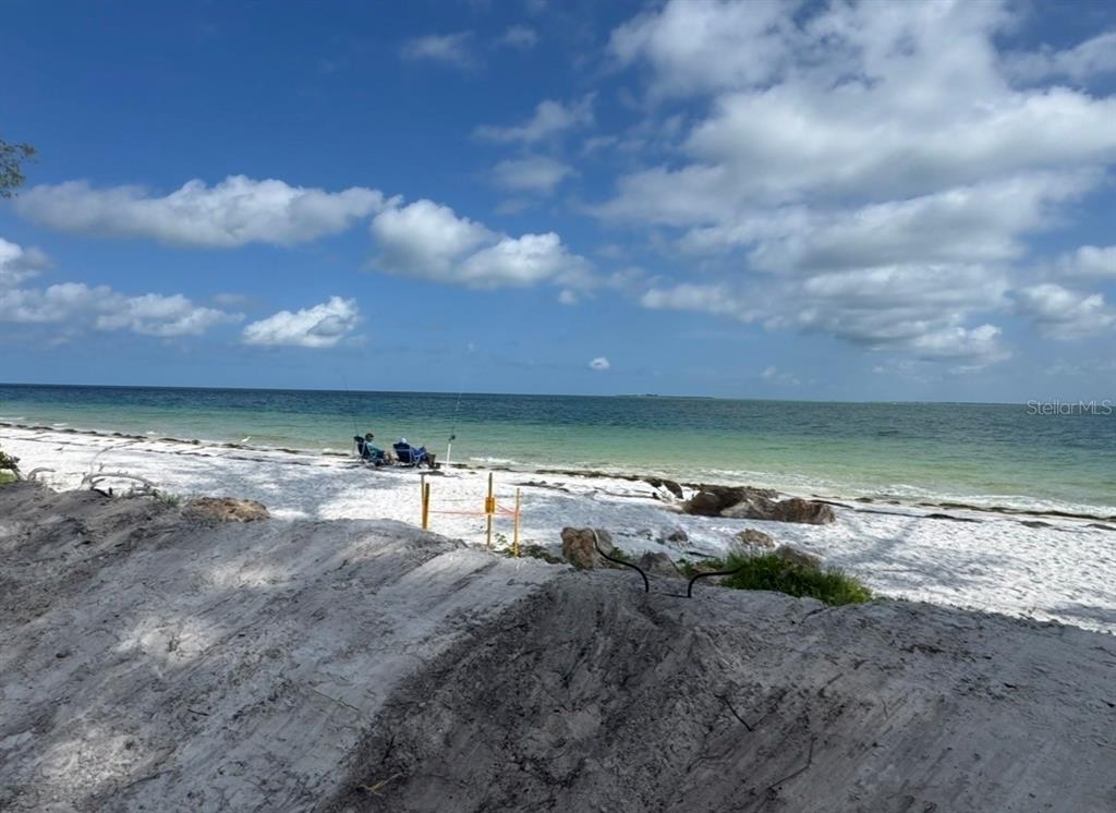 An aerial view shows a vacant sandy lot situated between two houses with metal roofs — 831 NORTH SHORE DRIVE, ANNA MARIA, FL