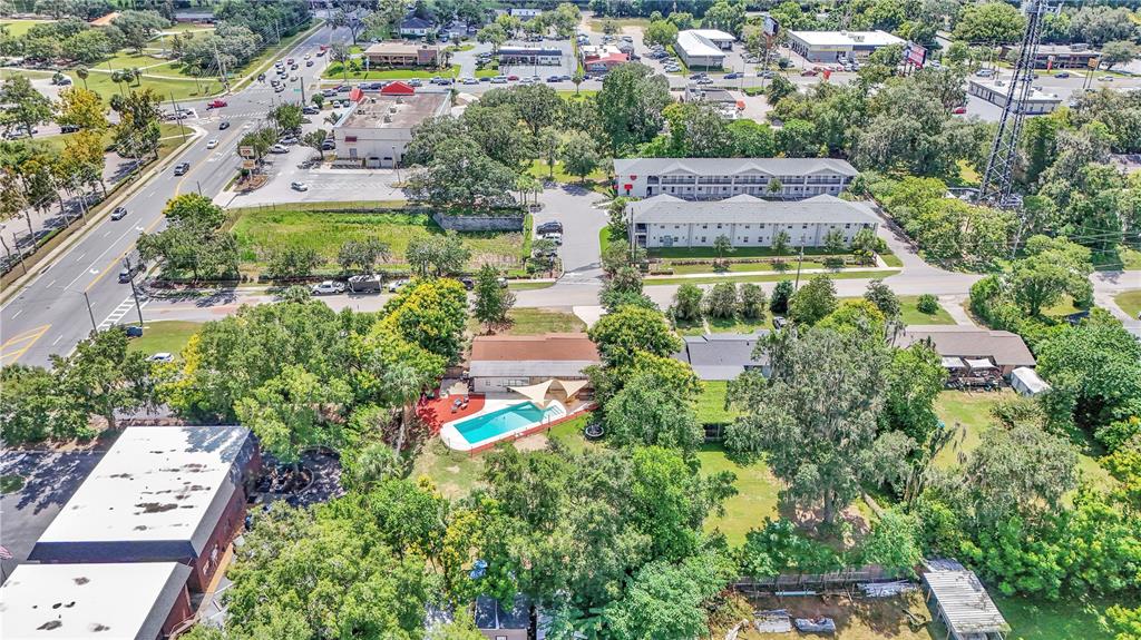 An aerial view shows a house with a swimming pool surrounded by trees and roads — 2433 NE 2ND STREET, OCALA, FL