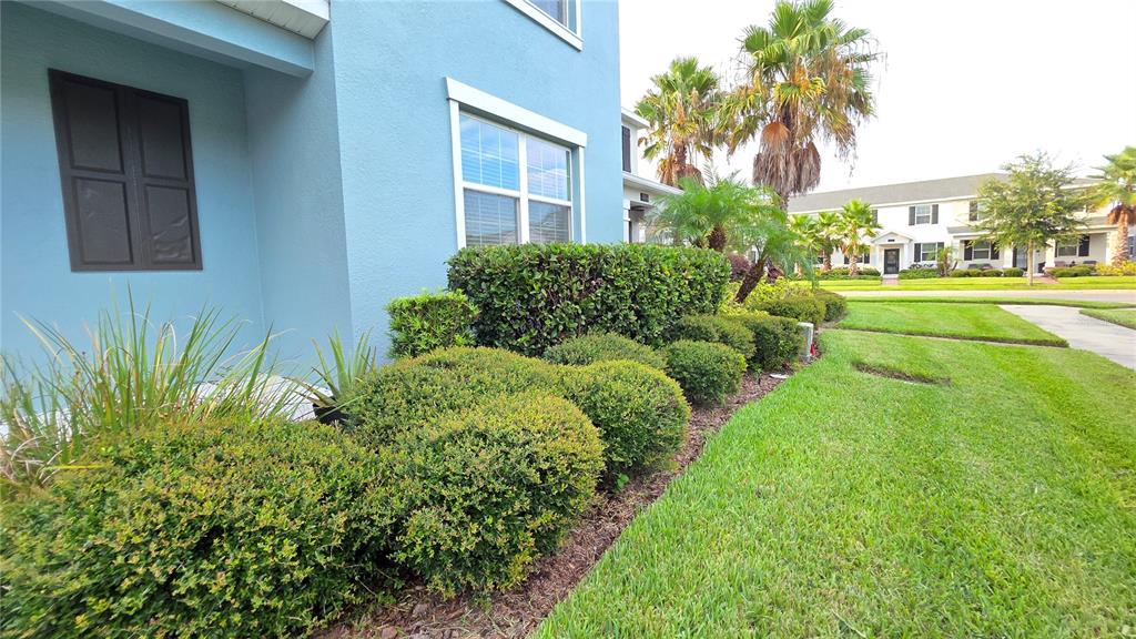 A two-story blue house features a covered entryway, a brick walkway, and landscaped front bushes — 11883 PULITZER PLACE, ORLANDO, FL