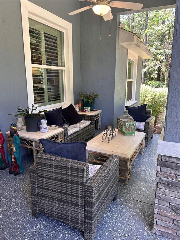 A covered patio features wicker furniture, stone-topped tables, and a ceiling fan — 12396 SW 61ST PLACE ROAD, OCALA, FL