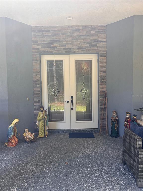 A covered entryway features double glass doors, stone veneer siding, and a nativity scene display — 12396 SW 61ST PLACE ROAD, OCALA, FL