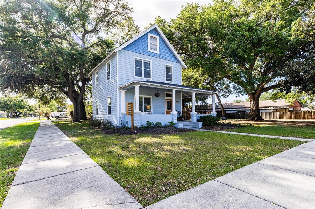A two-story blue house with a front porch sits on a grassy corner lot — 1320 JERSEY AVENUE, ST CLOUD, FL