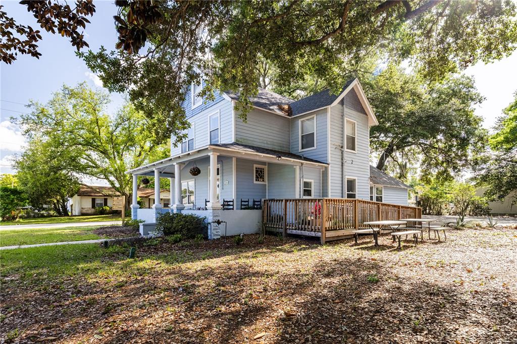 A two-story light blue house features a wrap-around porch and a wooden deck — 1320 JERSEY AVENUE, ST CLOUD, FL