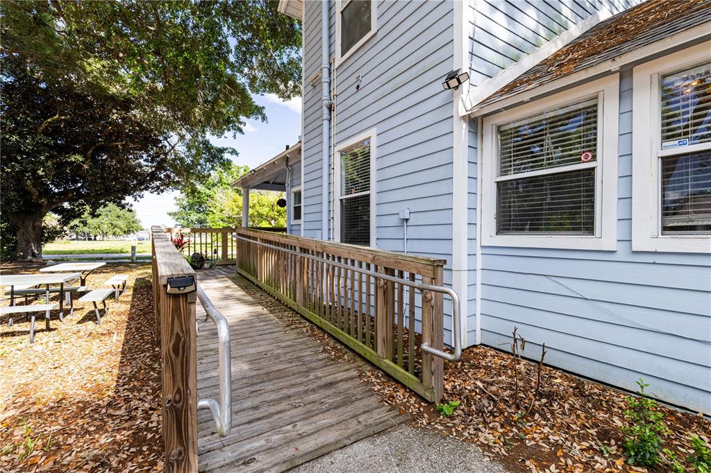 A wooden wheelchair ramp leads up to the side of a light blue house — 1320 JERSEY AVENUE, ST CLOUD, FL