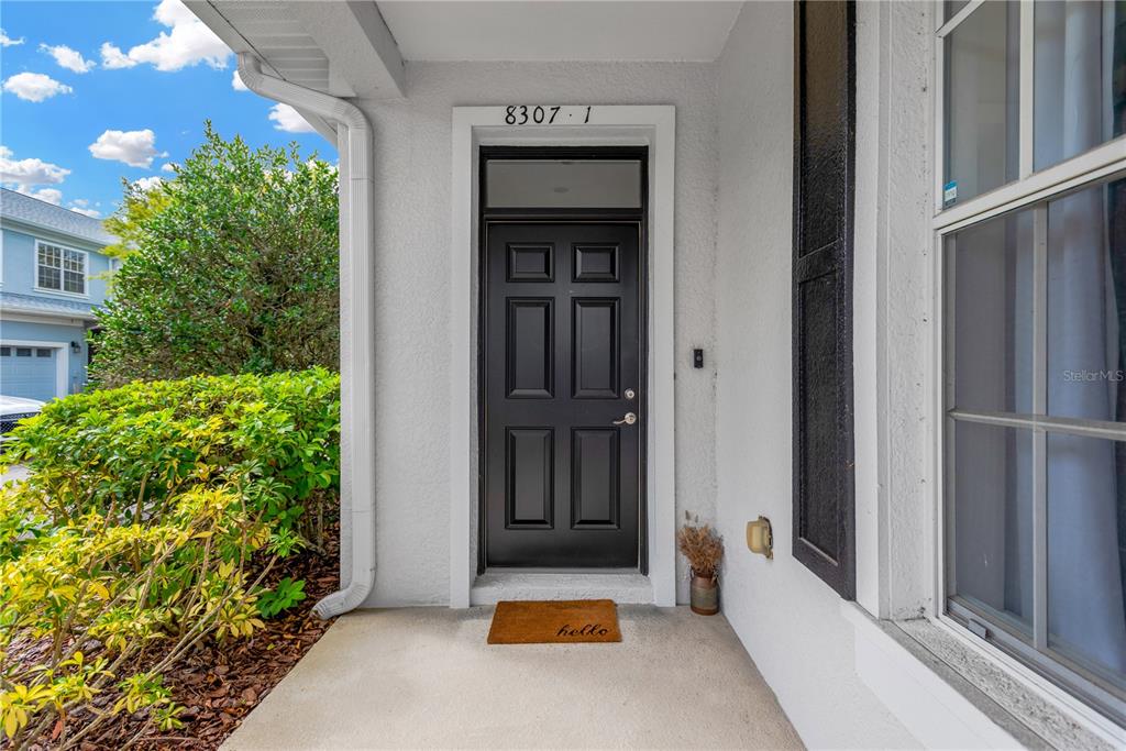 A black front door with a transom window sits under a covered entryway — 8307 MANOR CLUB CIRCLE UNIT 1, TAMPA, FL