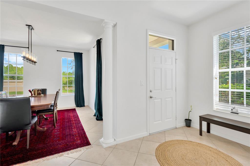 A dining room with a red rug and a foyer with a white door — 8307 MANOR CLUB CIRCLE UNIT 1, TAMPA, FL
