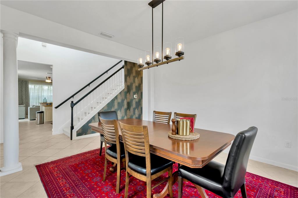 A dining room features a wooden table, chairs, a red rug, and a staircase — 8307 MANOR CLUB CIRCLE UNIT 1, TAMPA, FL