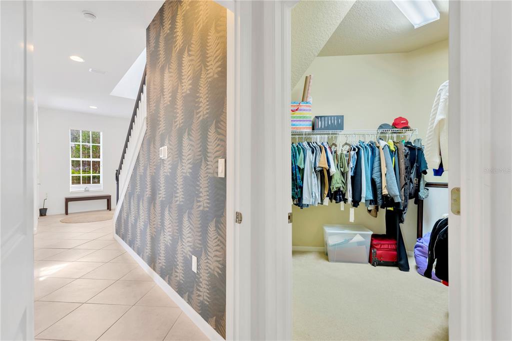 A view from a doorway into a closet with hanging clothes next to a hallway — 8307 MANOR CLUB CIRCLE UNIT 1, TAMPA, FL