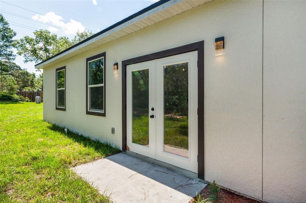 A white exterior wall features a set of French doors and two windows — 149 HICKORY AVENUE, ORANGE CITY, FL