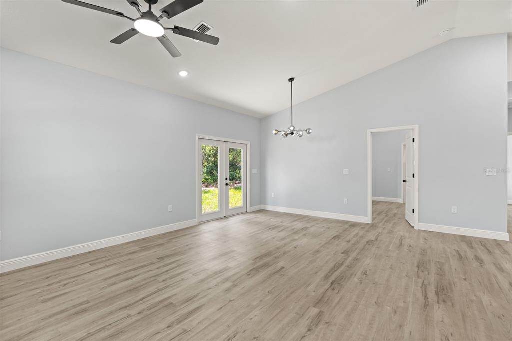 An empty room with light wood-look flooring, a ceiling fan, and glass French doors — 149 HICKORY AVENUE, ORANGE CITY, FL