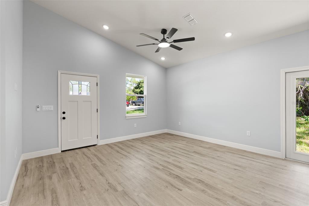 An empty room with light gray walls, wood-look flooring, a ceiling fan, and two doors — 149 HICKORY AVENUE, ORANGE CITY, FL