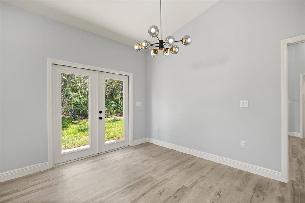 A dining room with light gray walls, wood-look flooring, a modern chandelier, and French doors — 149 HICKORY AVENUE, ORANGE CITY, FL