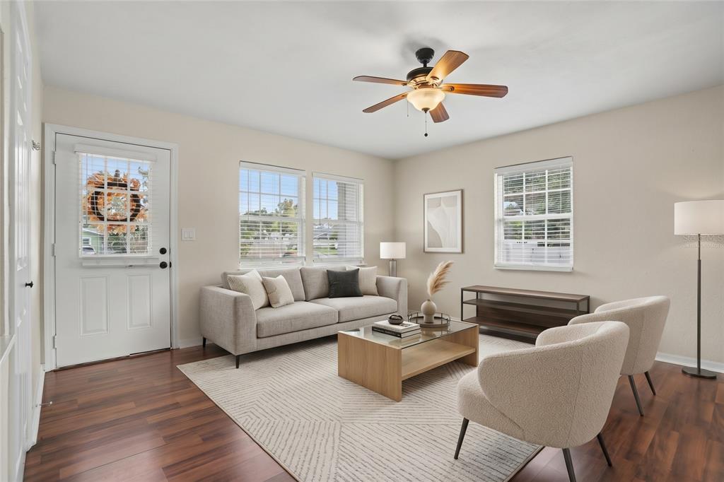 An empty room features wood-look flooring, beige walls, a ceiling fan, and three windows — 5210 4TH AVENUE N, ST PETERSBURG, FL