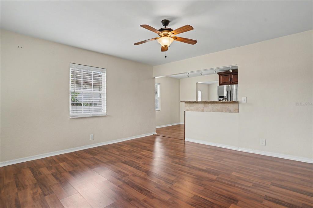 A living room with wood-look flooring, a ceiling fan, and a pass-through to the kitchen — 5210 4TH AVENUE N, ST PETERSBURG, FL