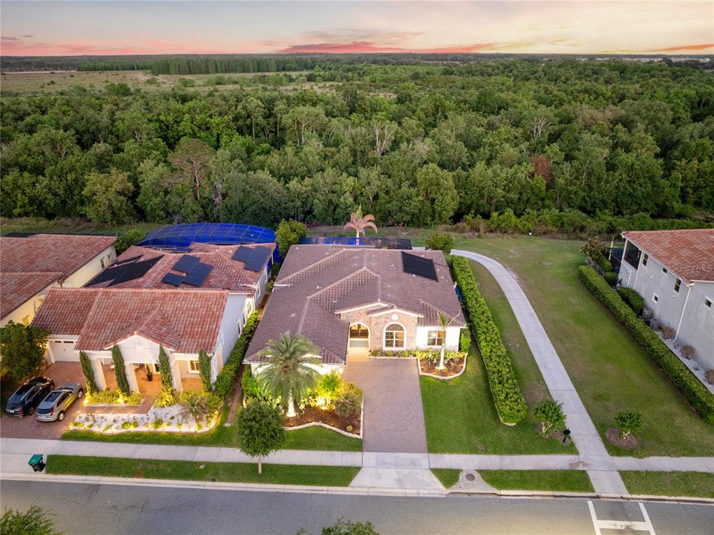 A single-story house with a stone facade, tile roof, and a paved driveway at dusk — 13391 ALDERLEY DRIVE, ORLANDO, FL
