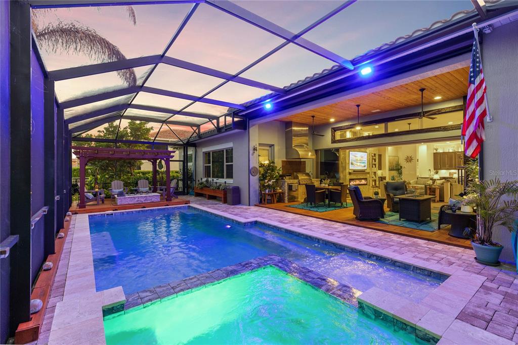 A covered outdoor patio features a swimming pool, dining area, and built-in stainless steel grill — 13391 ALDERLEY DRIVE, ORLANDO, FL